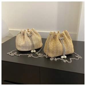 Détail de sacs seaux en paille avec cordons en perles et bandoulières en chaîne