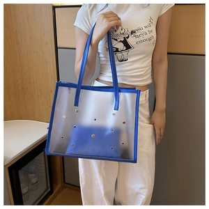 Detail view of blue semi-transparent frosted PVC tote bag with stylish rainbow rivets