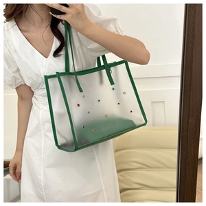 Detail of transparent PVC tote bag with green PU handles and colorful rhinestones