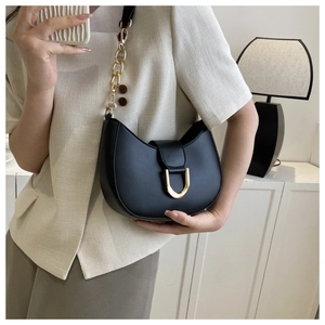 Fashionable black half-moon shoulder bag with golden horseshoe buckle worn by model