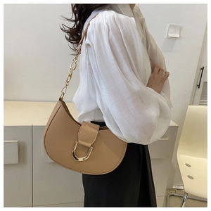 Detail of khaki crescent saddle bag featuring a large gold metal U-buckle and chain strap