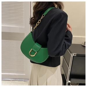 Detail of green half-moon saddle bag showing gold horseshoe clasp and chain strap