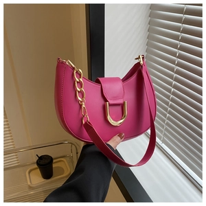 Detail of rose pink crescent bag featuring a gold D-buckle and elegant chain strap