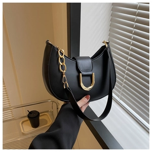 Detailed shot of black half-moon saddle bag with golden metal buckle and chain detail