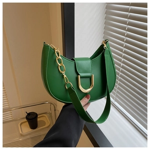 Detail view of emerald green crescent bag with gold D-buckle and decorative metal chain