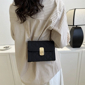 Classic black quilted chain bag with gold twist lock worn as a crossbody by a model