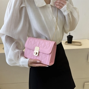 Pink quilted crossbody bag with gold chain strap and turn-lock closure on a model
