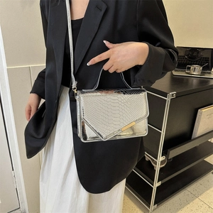 Zilveren crossbodytas met slangenpatroon, metallic glans en gouden details op model