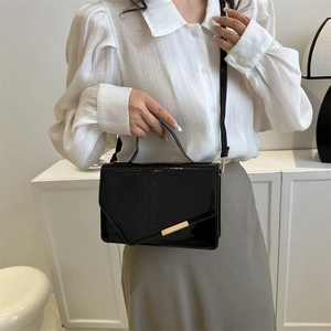 Glanzende zwarte crossbodytas met krokodillenpatroon en gouden hardware detail