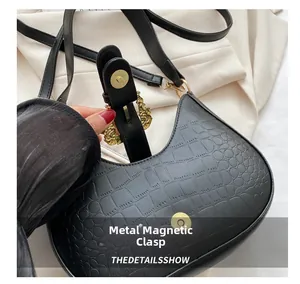 Detailed macro view of black croc-embossed leather texture and golden magnetic hardware clasp