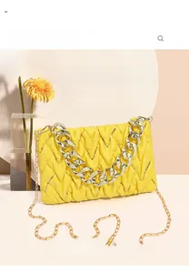 Detail einer gelben gesteppten Handtasche mit goldener Kette und Blumendekoration