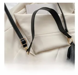 Detail of adjustable gold buckle and embossed faux crocodile leather on black shoulder bag
