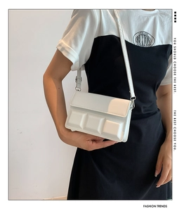 Detail of white chocolate-textured shoulder bag with magnetic flap and slim strap