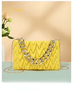 Detail der gelben gesteppten kleinen quadratischen Tasche mit goldener Kette
