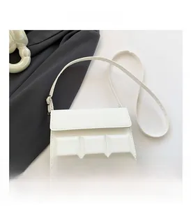 Close-up of white crossbody bag featuring geometric square pattern and silver hardware