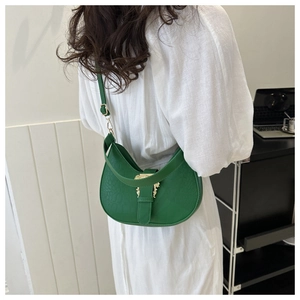 Detailed view of crocodile pattern underarm bag with gold relief buckle on green leather