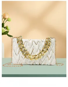 Details der weißen Plissee-Handtasche mit goldener Gliederkette und schmalem Schultergurt