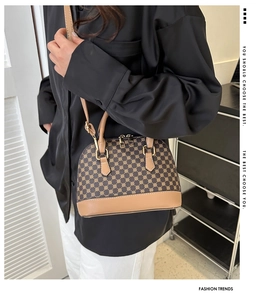 Retro schelpvormige tas met monogramprint en lichtbruine lederen bies op model