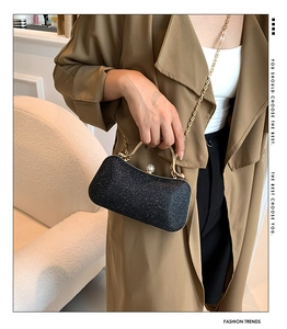 Close-up of elegant black glitter evening bag with gold handle and metal chain strap