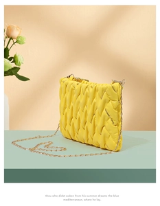 Detail der gelben Webstruktur und Goldkette einer modischen gesteppten Umhängetasche