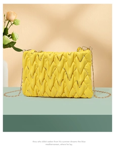 Detail der gelben Stepptasche mit goldenen Pailletten und Metallkette auf Mint-Ständer