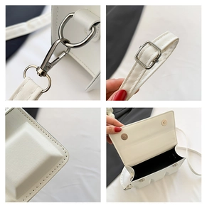 Detail of white leather shoulder bag featuring silver hardware and dual magnetic closures