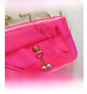 Détail du sac en PVC transparent rose néon avec chaîne dorée et fermoir à perles