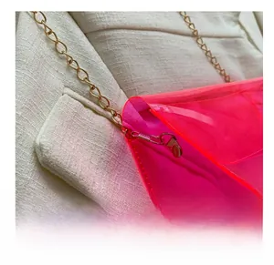 Détail du sac en PVC rose fluo avec bandoulière chaîne dorée et crochets en métal