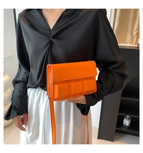 Detailed view of an orange crossbody bag with 3D geometric squares and adjustable strap
