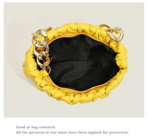 Innenansicht der gelben gefalteten Tasche mit goldener Kette und schwarzem Futter