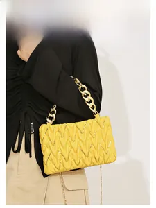 Detail der leuchtend gelben V-gesteppten Tasche mit Pailletten und goldener Kette