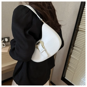 Detail of white crocodile pattern shoulder bag with vintage gold buckle on model