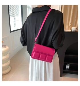 Detail view of hot pink crossbody bag with padded squares worn on a model back