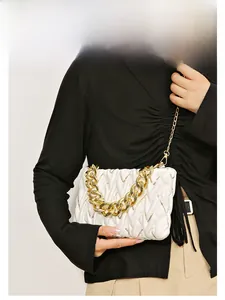 Detail einer weißen Stepptasche mit gewebten Falten und klobiger goldener Kette
