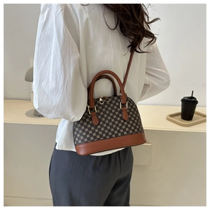 Brown monogram shell bag worn as a shoulder bag by a model in a minimalist room