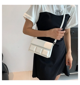 Side view of white crossbody bag with 3D geometric squares on a female model