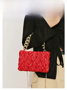 Detail der roten gesteppten Handtasche mit goldener Kette und glänzenden Pailletten