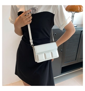 Close-up of white crossbody bag with 3D embossed grid pattern and adjustable strap