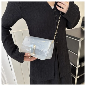 Détail du sac bandoulière en PVC transparent avec chaîne dorée et pendentif en perles