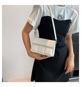 Detailed view of a white crossbody bag with 3D chocolate square texture on a model