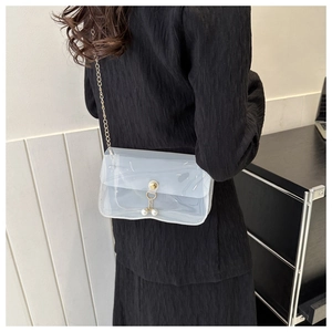 Détail du sac bandoulière en PVC transparent avec chaîne dorée et breloques perles