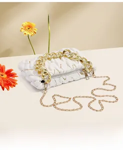 Detailansicht einer weißen gesteppten Cloud-Tasche mit klobiger Goldkette und Blumen