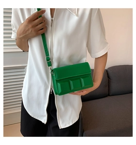 Detail of a bright green leather crossbody bag with modern 3D square embossed design