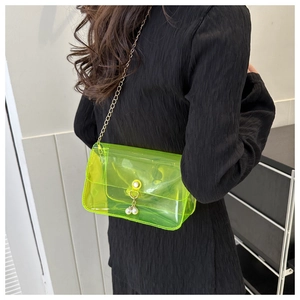 Détail du sac transparent en PVC vert néon avec chaîne dorée et perles sur un modèle