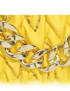Makro-Detail der gelben gesteppten Ledertasche mit goldener Kette und Paillettenverzierung