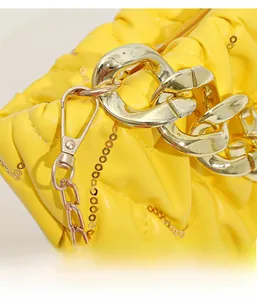Nahaufnahme der gelben Plissee-Tasche mit vertikalen Pailletten und goldener Gliederkette