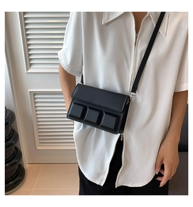 Close-up of a black square crossbody bag with 3D embossed cubes and sleek flap closure