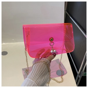 Détail d'un sac transparent en PVC rose avec chaîne dorée et fermoir à perles