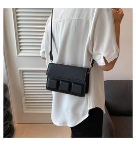 Detail of black crossbody bag with embossed chocolate pattern shown on a model