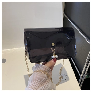 Détail du sac en PVC transparent noir avec bandoulière dorée et breloque perle